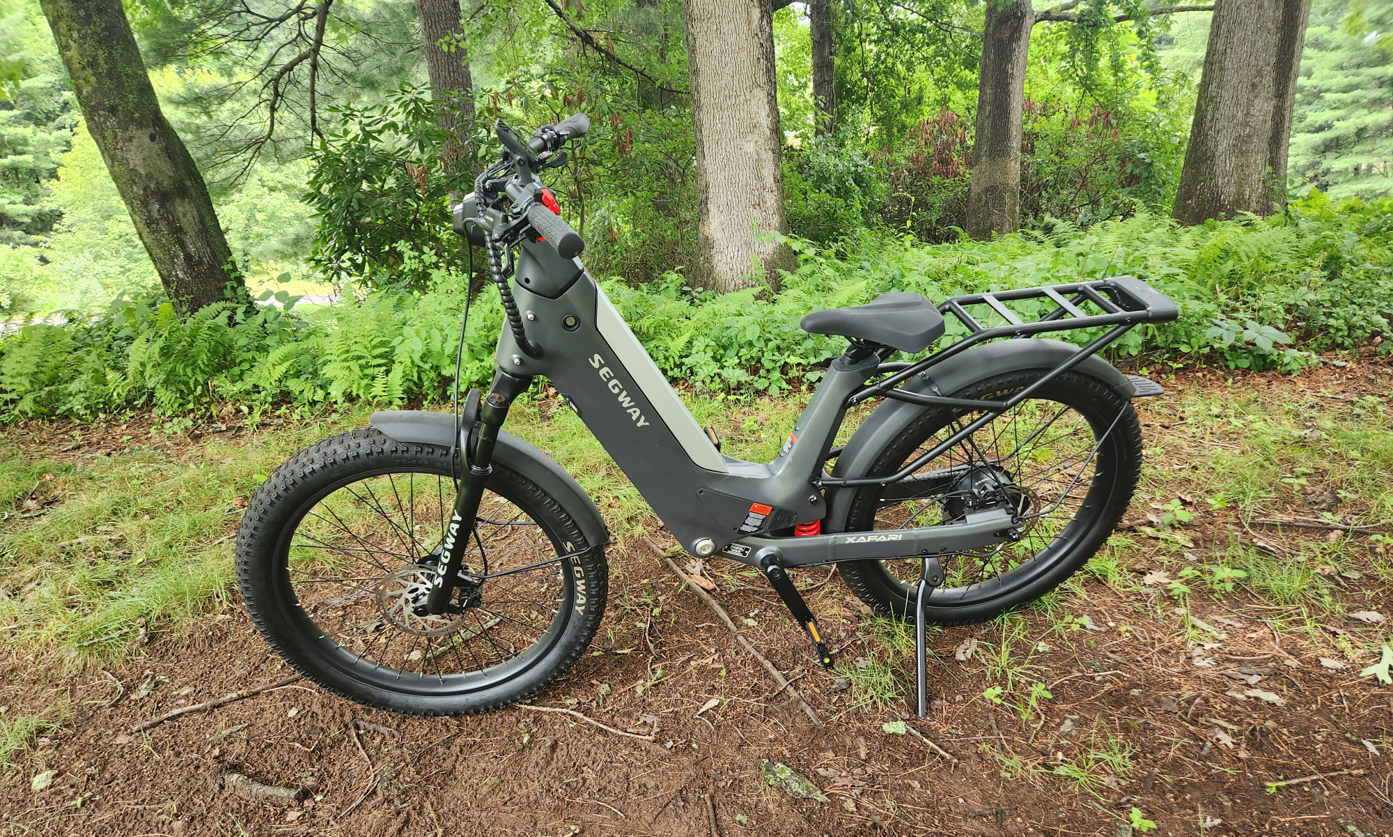 Segway Xafari e-bike left side parked on a grassy hill with trees in the background.