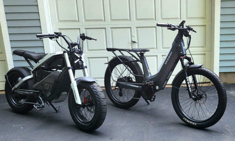 Segway Xyber and Xafari e-bikes parked in front of a white garage door.
