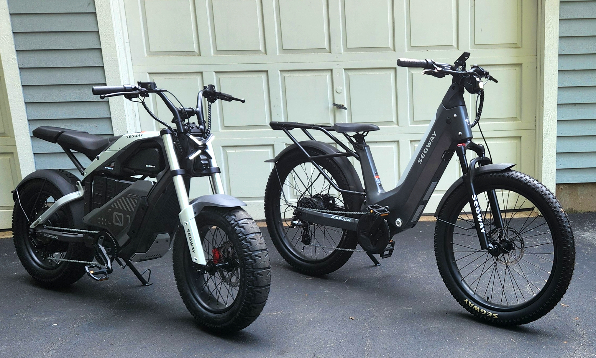 Segway Xyber and Xafari e-bikes parked in front of a white garage door.