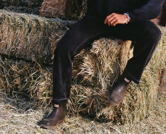 man wearing hunter x represent boots on hay bale