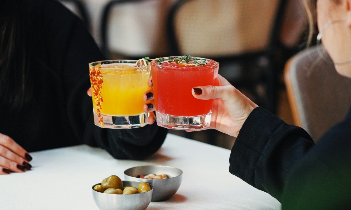 Two people toasting with cocktails