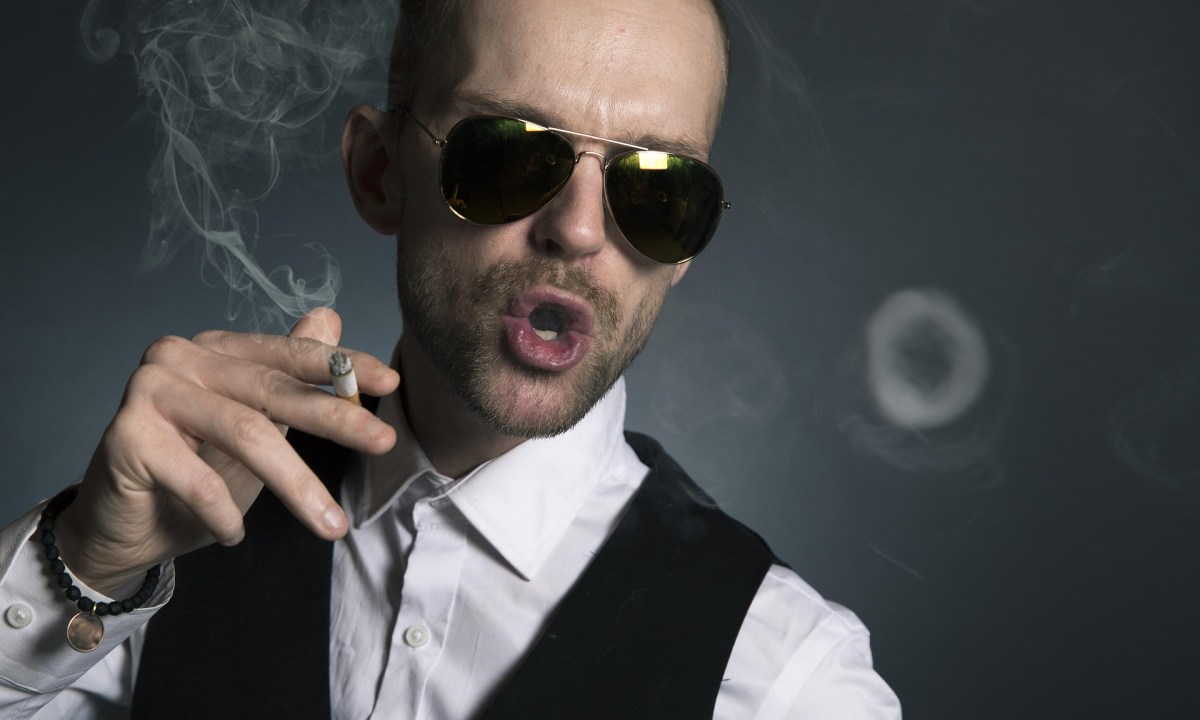 man in shades blowing a smoke ring