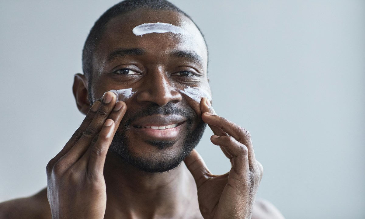 a man putting cream on face and smiling