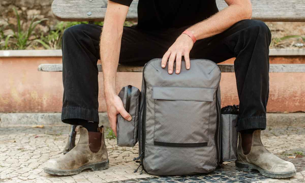 man sitting on bench with meridian backpack from the brand mission workshop
