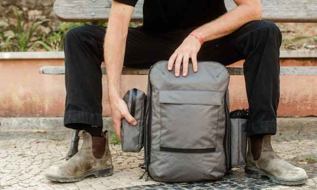 man sitting on bench with meridian backpack from the brand mission workshop