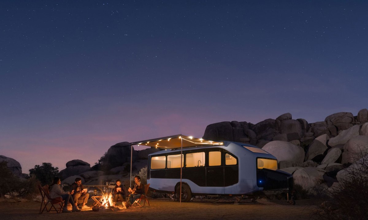 Campers sitting outside a Pebble Flow electric RV at night.