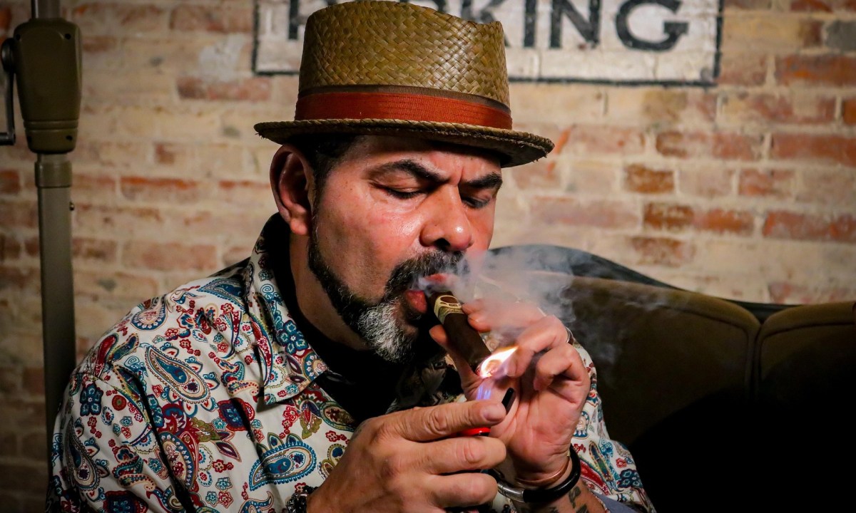 Man wearing top hat lighting a cigar in a bar