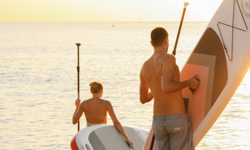 man and woman paddleboarding holding boards