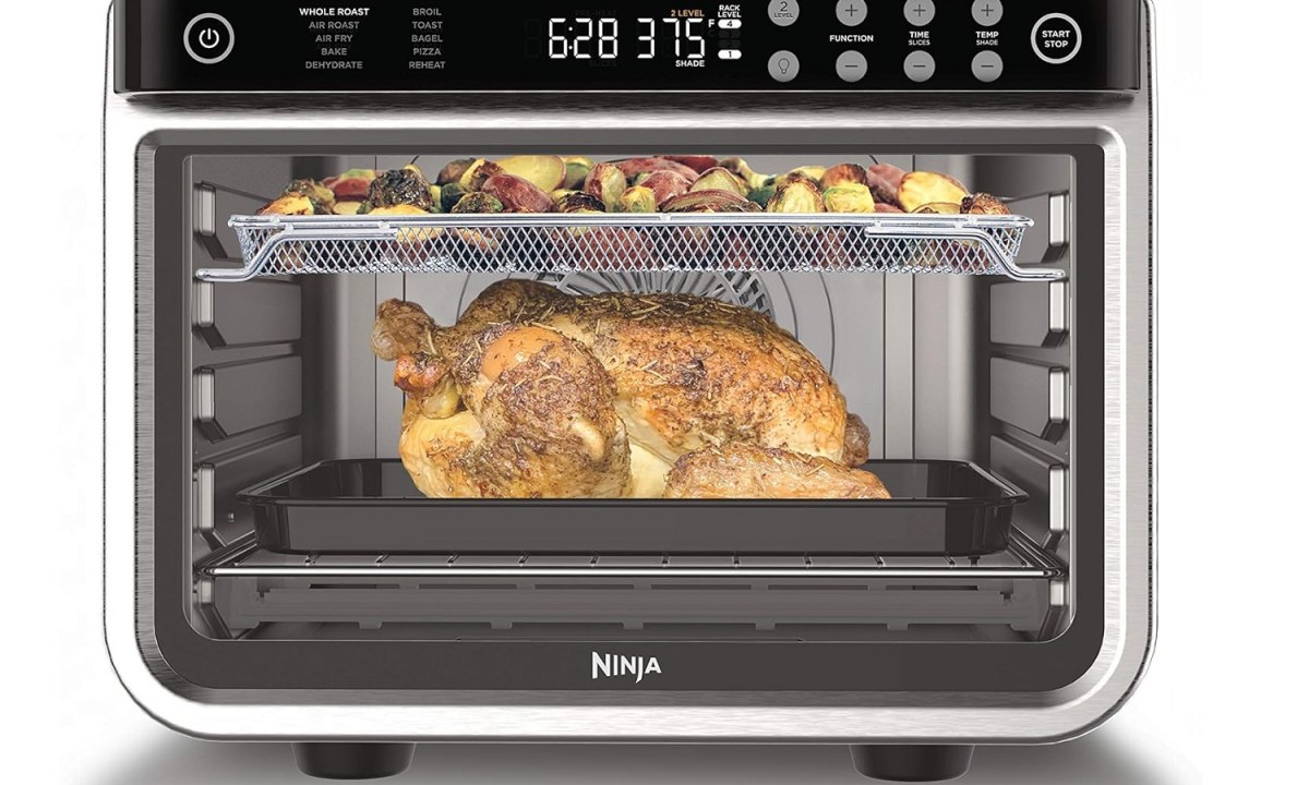 The Ninja Foodi XL Pro Air Over air fryer and toaster oven with vegetables and chicken inside.