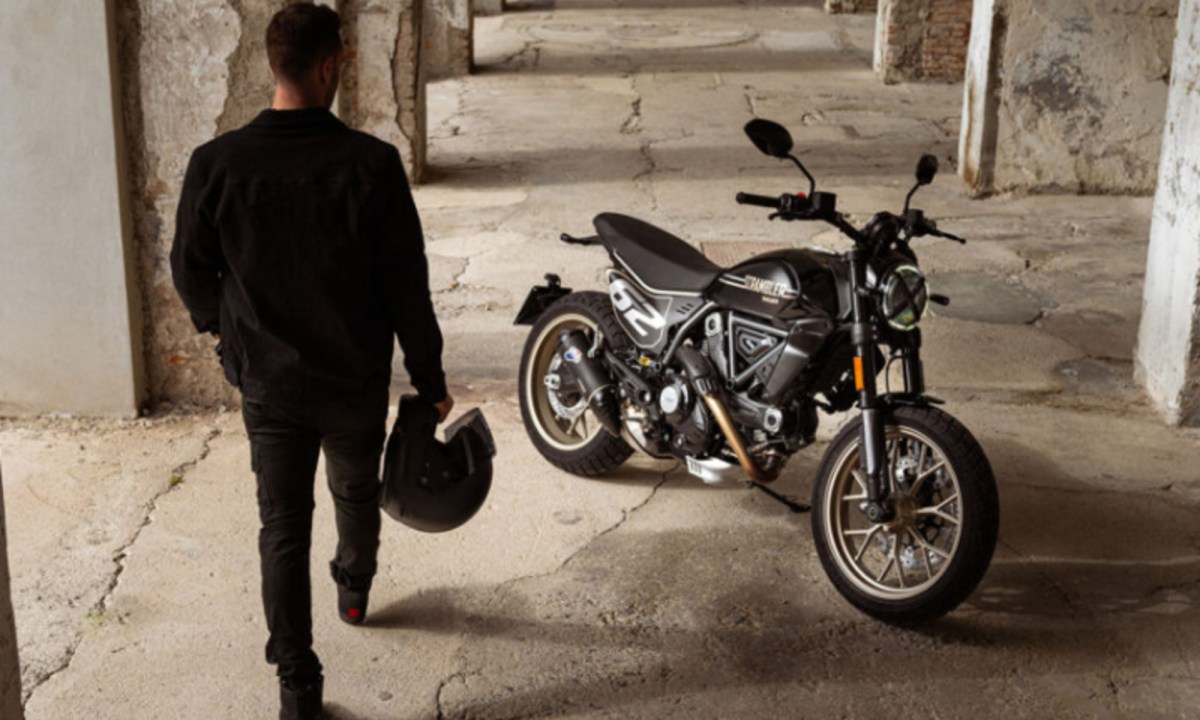 Rider with helmet approaching a 2025 Ducati Scrambler Full Throttle.