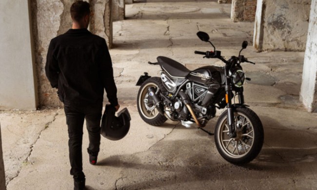 Rider with helmet approaching a 2025 Ducati Scrambler Full Throttle.