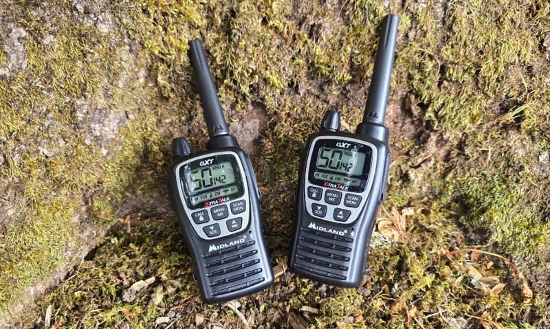 Two radios sitting on a mossy tree stump outside