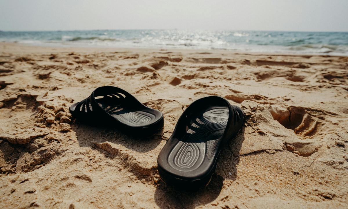 sandals on sand near ocean