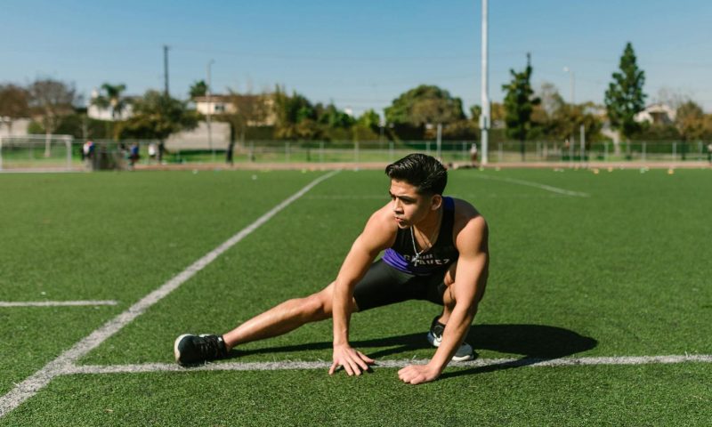 man exercising stretching on field
