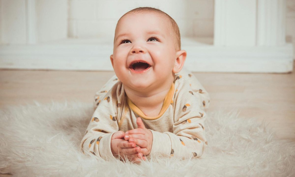 baby smiling happy laying on floor belly