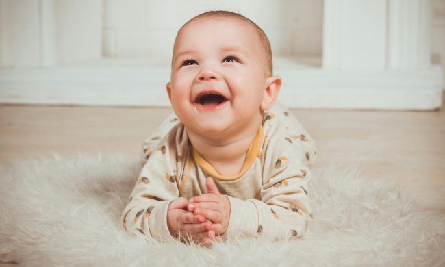 baby smiling happy laying on floor belly