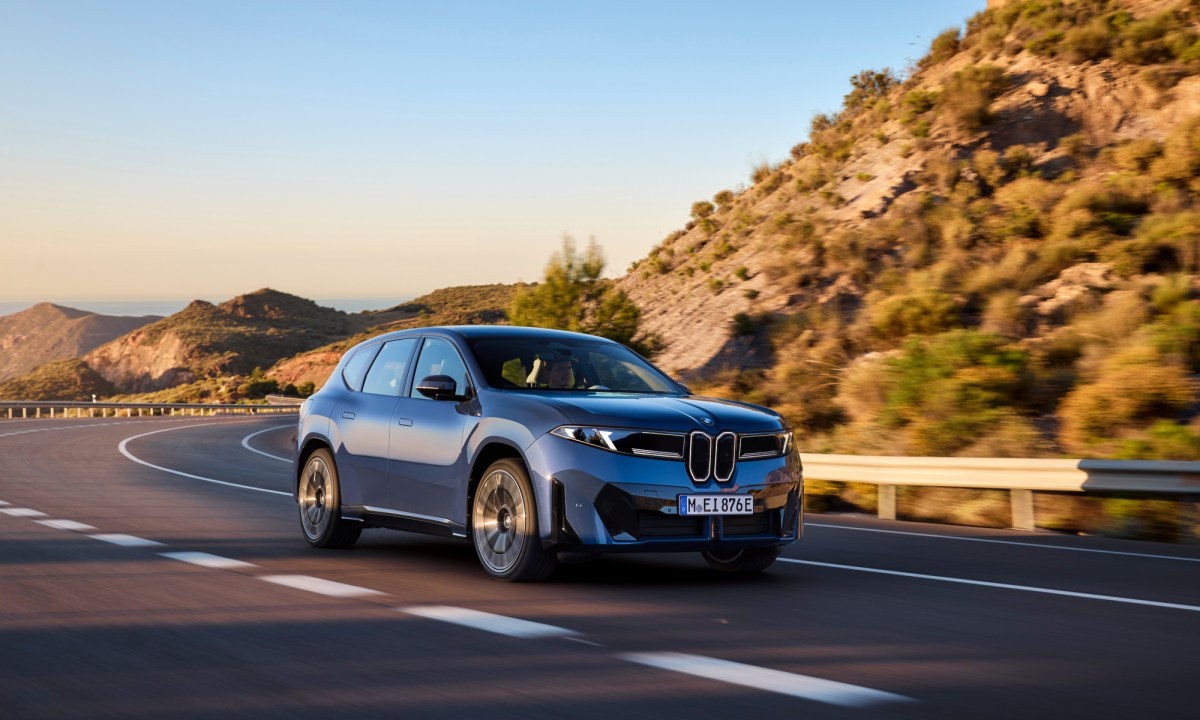 2026 BMW iX3 50 exterior right front three quarter view driving on a mountain highway.