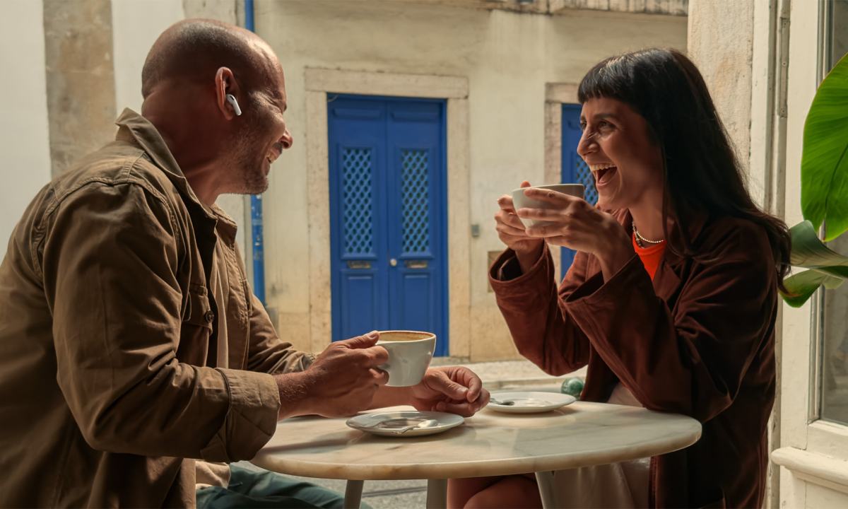 Two people conversing in a cafe while wearing AirPods Pro 3