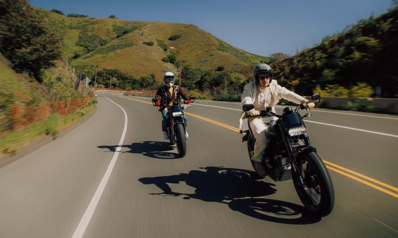 Two riders on LiveWire S2 Del Mars on a highway with rolling hills in the background.